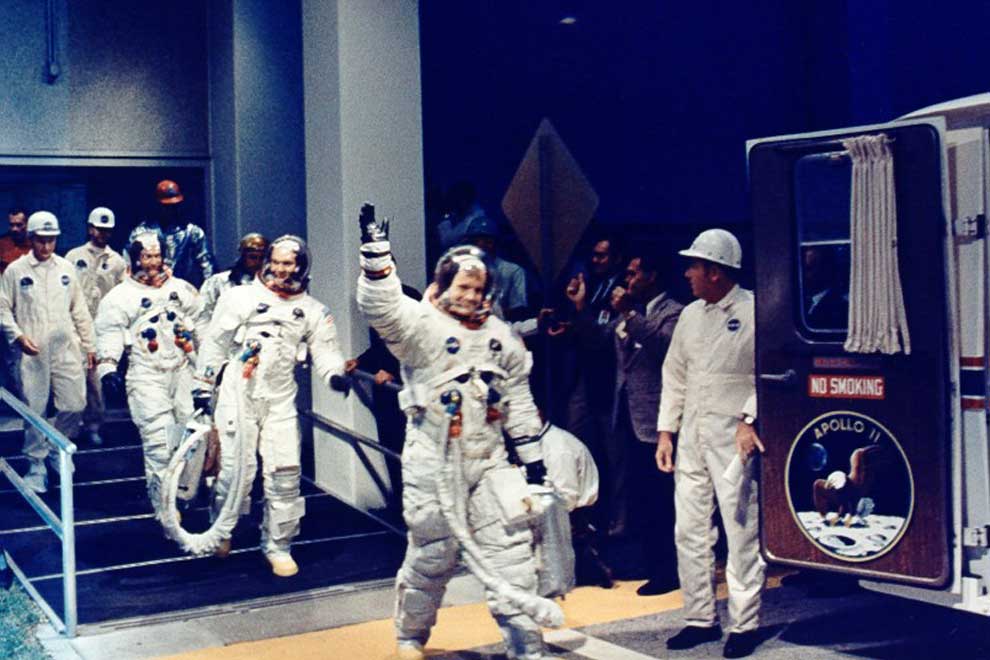 Armstrong, Aldrin y Collins salen del edificio de operaciones de naves espaciales tripuladas para entrar en la furgoneta de transferencia. Foto: NASA.